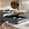 A bed with its storage compartment open, showing a remote control and USB ports. Produktbild-Vorschau