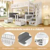 A white loft bed with a desk, seating area, and storage stairs, set in a room with natural light and some decorative elements. Produktbild-Vorschau