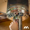 A child's hand is shown adjusting the knob on a gas patio heater. Náhled obrázku produktu