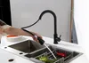 A person is using a black pull-down kitchen faucet to rinse vegetables in a sink. Anteprima dell’immagine prodotto