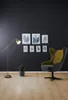 A modern living room corner with a floor lamp, a plant, a framed art collection, and an armchair. Produktbild-Vorschau
