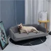 A French Bulldog is relaxing on a dark gray dog sofa in a living room setting. There is a small yellow side table with books on it in the background. Podgląd zdjęcia produktu