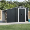 A dark gray metal shed with a side storage area for firewood, set in a grassy yard with a wooden fence. Náhľad obrázku produktu