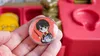 A hand holding a Harry Potter themed button with a cartoon character of Harry Potter on it. In the background, there is a red plastic container and some yellow objects. Anteprima dell’immagine prodotto