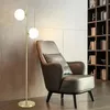 A modern living room with a floor lamp and an armchair next to a bookshelf. Náhľad obrázku produktu