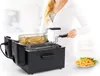 A woman is using a black deep fryer that contains french fries. Another plate of french fries is on the right. Produktbild-Vorschau