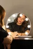 A woman is looking into a lighted makeup mirror. Podgląd zdjęcia produktu