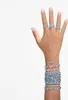 A hand adorned with multiple Swarovski bracelets and rings, showcasing the Matrix Tennis collection in silver and blue. Voir les images du produit