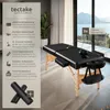 A black massage table set up in a room with a large window overlooking a body of water and mountains. Náhled obrázku produktu