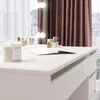 A close-up view of a white vanity table with several perfume bottles and a candle. Voir les images du produit