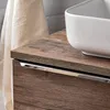 A close-up view of a bathroom vanity with a wooden finish and a white ceramic sink. Produktbild-Vorschau