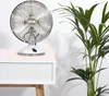 A white table fan sits on a white dresser next to a green potted plant. Produktbild-Vorschau