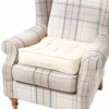 A close-up view of a cream-colored cushion placed on a plaid armchair. Produktbild-Vorschau