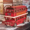 A 3D wooden model of a red London double-decker bus is displayed on a cobblestone-like surface, with blurred building structures in the background. Anteprima dell’immagine prodotto