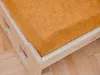 A close-up view of a crib mattress with an orange fitted sheet, placed on a wooden crib frame. Produktbild-Vorschau