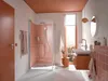 A modern bathroom with a walk-in shower, sink, and vanity, decorated in peach and white tones. Podgląd zdjęcia produktu
