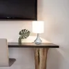 A desk with a lamp, a plant, and a chair. Náhľad obrázku produktu