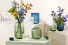 A collection of glass vases and candle holders with flowers and a candle, arranged on display surfaces. Náhled obrázku produktu