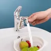 A hand is holding a faucet attachment, directing water into a colander filled with fruit and vegetables in a sink. Podgląd zdjęcia produktu