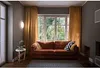 A living room with a sofa in front of a window. Produktbild-Vorschau
