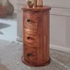 A wooden cylindrical cabinet with three drawers sits on a rug in a room. Podgląd zdjęcia produktu