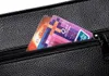 Close-up of a black textured bag with two cards sticking out of a zippered pocket. Náhľad obrázku produktu