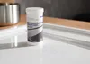 A white plastic bottle of BLANCO DeepClean Ceramic cleaner sits on a white surface, with a stainless steel bowl in the background. Produktbild-Vorschau