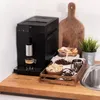 A coffee machine is shown on a wooden countertop next to coffee-related accessories. Produktbild-Vorschau