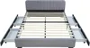 A grey upholstered bed frame with four drawers pulled out, shown from a slightly elevated front-left angle against a white background. Produktbild-Vorschau