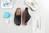 A flat lay of black Birkenstock clogs with red trim, along with dental tools and a dental retainer case. Anteprima dell’immagine prodotto
