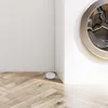 A close-up view of a washing machine drum and a small white object on a wooden floor. Anteprima dell’immagine prodotto