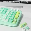 A close-up view of a pastel green keyboard with round keys, showing some of the number pad and other keys. Some keys are removable, and a few are shown detached. Podgląd zdjęcia produktu