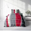 A bed with plaid bedding in a room with a floor lamp and a nightstand with flowers. Produktbild-Vorschau
