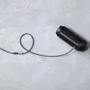 A black audio cable plugged into a black speaker on a gray concrete surface. Produktbild-Vorschau