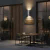 An outdoor seating area at night with a wall lamp and a sign. Podgląd zdjęcia produktu