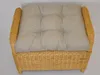A close-up, straight-on view of a wicker ottoman with a tufted cushion. Produktbild-Vorschau