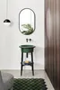 A modern bathroom scene with a green sink and black stand, a mirror, and a patterned rug. Produktbild-Vorschau