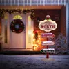 A Christmas-themed directional signpost in front of a decorated house entrance at night. Podgląd zdjęcia produktu