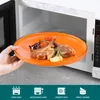 A hand is placing a plate of food into a microwave. Produktbild-Vorschau