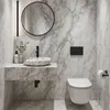 A modern bathroom with marble walls and floor, featuring a wall-mounted vanity with a vessel sink and a toilet. Náhled obrázku produktu