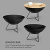 A collage showing a black metal fire pit in three different configurations: as a standalone fire pit, as a grill with a grate, and as a table with a wooden top and a coffee cup and book on it. Produktbild-Vorschau
