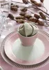 A table setting with plates, a napkin in a bowl, and decorative branches. Produktbild-Vorschau