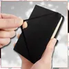 A close-up shot of a black mini-notebook with an elastic band being held by two hands. Náhľad obrázku produktu
