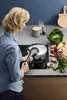 A woman is using a pressure cooker on a stovetop in a modern kitchen. Náhled obrázku produktu