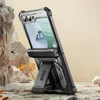 A rugged phone case with a built-in stand is displayed on a rocky surface with some dry leaves. Produktbild-Vorschau