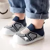 Kleinkindfüße in blau-weiß gemusterten Schlüpfschuhen mit weißen Sohlen, mit umgeschlagenen blauen Jeans Náhled obrázku produktu