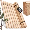 A stack of wooden bed slats leans against a white background, with a small tree on the left and a portion of a roll of slats on the right. Produktbild-Vorschau