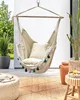 A hanging chair with tassels on a patio with plants and furniture. Náhled obrázku produktu