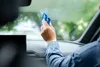 A person is cleaning a car windshield with a blue squeegee. Produktbild-Vorschau
