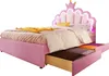 A pink princess-themed bed with a crown-shaped headboard and built-in LED lighting, shown with two open drawers underneath. Voir les images du produit